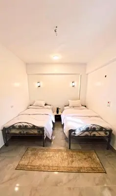 two twin beds in a room with a rug at Dreams By Mon in Al Karnak