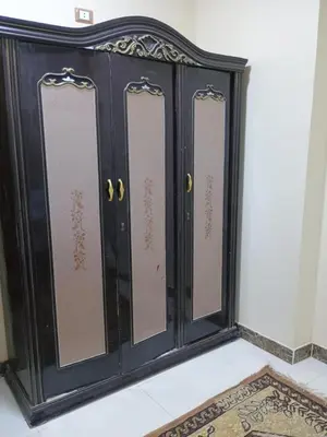 a black cabinet with four doors on a wall at Families only in Al ‘Izbah wa al ‘Arab