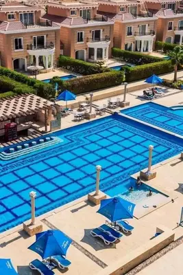 an overhead view of a swimming pool with blue chairs and umbrellas at Selena bay resort in Hurghada