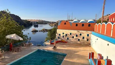 a pool on the side of a building next to a river at Cataract Nile View Rooms in Shellal