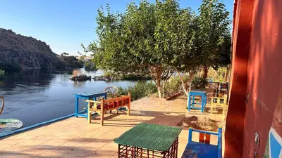 a patio with tables and chairs next to a river at Cataract Nile View Rooms in Shellal