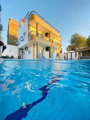 a person swimming in the water in front of a building at Villa Luna Simone in Al Karnak