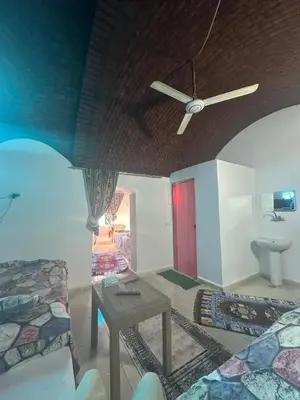 a living room with a ceiling fan and a table at Nubia House Nile View in Nag` el-Ramla