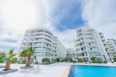 two white apartment buildings with a swimming pool and palm trees at Scandic sea view in Hurghada