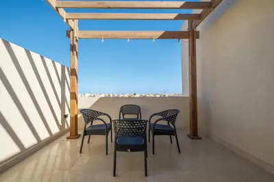 a balcony with chairs and a table and a window at Brand New Shedwan Spacious 1Bdr in Hurghada