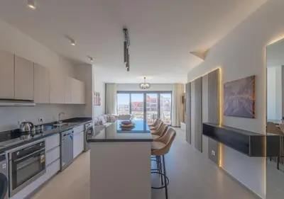a kitchen with white cabinets and a kitchen island with bar stools at Sophisticated 1BR 1,5 Bath Duplex - Kamaran El Gouna, Pool View & Access in Hurghada