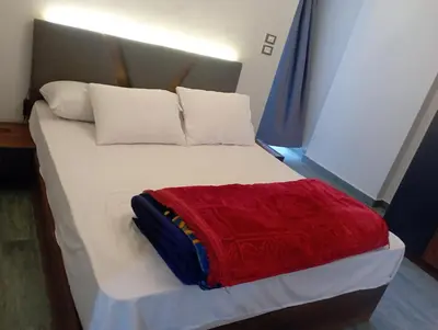 a large white bed with a red blanket on it at شقه على النيل in Luxor