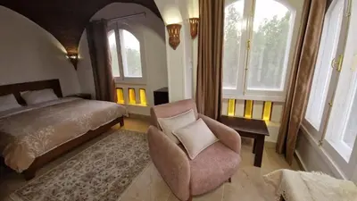 a bedroom with a bed and a chair and windows at House Mountain Luxor - Villa for rent in Luxor