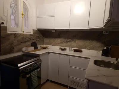 a kitchen with white cabinets and a stove and a sink at House Mountain Luxor - Villa for rent in Luxor