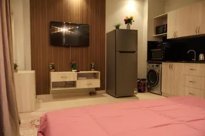 a kitchen with a refrigerator and a tv on a wall at Cosy studio Florenza khamsin in hurghada in Hurghada