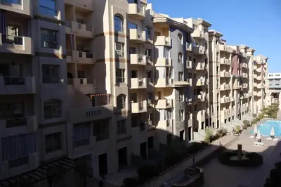 an apartment building with a swimming pool in front of it at Cosy studio Florenza khamsin in hurghada in Hurghada