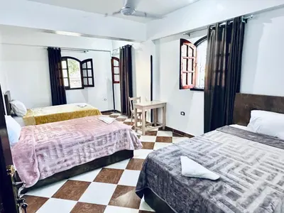 a bedroom with two beds and a checkered floor at Golden Rose Guesthouse in Luxor