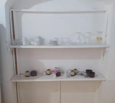 a white shelf with dishes and cups on it at Old Nile Retreat in Luxor