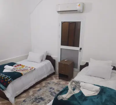 a room with two beds and a table and a window at Old Nile Retreat in Luxor