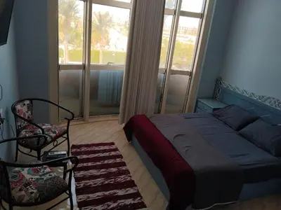 a bedroom with a bed and a chair and a window at Andalus in in Hurghada