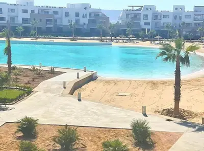 a large swimming pool with palm trees and buildings at Spacious 2 BD with crystal Lagoon access in Gouna in Hurghada