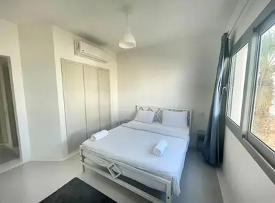 a bedroom with a bed with white sheets and a window at Spacious 2 BD with crystal Lagoon access in Gouna in Hurghada