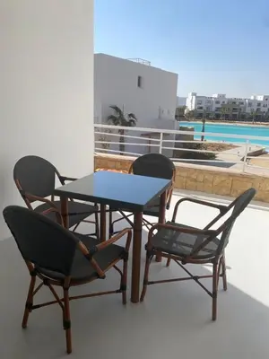 three chairs and a table on a balcony at Spacious 2 BD with crystal Lagoon access in Gouna in Hurghada