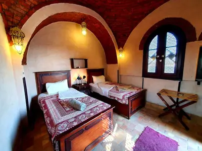 a bedroom with two beds in a room with two windows at Riverbank House in Luxor