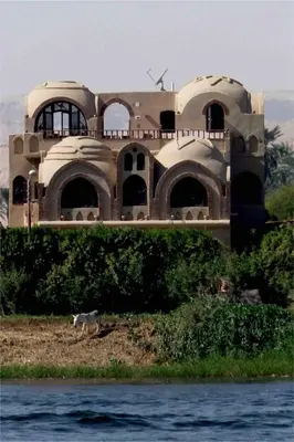 a dog walking in front of a building next to the water at Riverbank House in Luxor