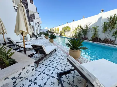 a swimming pool with chairs and umbrellas next to a building at Arаbian Suites by Imperial in Hurghada