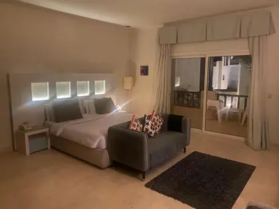 a bedroom with a bed and a couch and a chair at Cozy studio in Azzurra Resort Sahl Hasheesh 65 Sq M in Hurghada