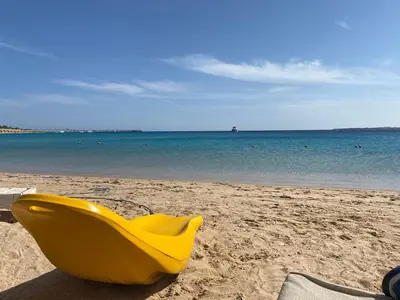 a yellow plastic chair sitting on the beach at Cozy studio in Azzurra Resort Sahl Hasheesh 65 Sq M in Hurghada