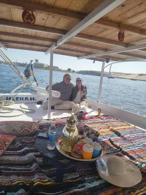 two people sitting on a boat with a tray of food at Sunset and Sand Felucca Life on the Nile in Jazīrat Aswān