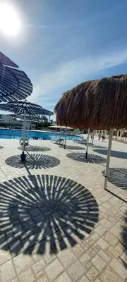 a shadow of a straw umbrella on a beach at Minaland Beach Resort & Aquapark in Hurghada