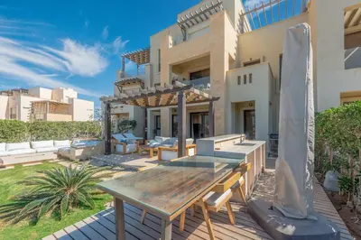 a patio with a wooden table in front of a house at Serene Lakeview Escape 2BR at Cyan ElGouna in Hurghada