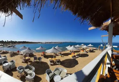a beach with chairs and umbrellas and the ocean at Hurghada Apartment Makadi Lagon & Swimming Pools Free in Hurghada