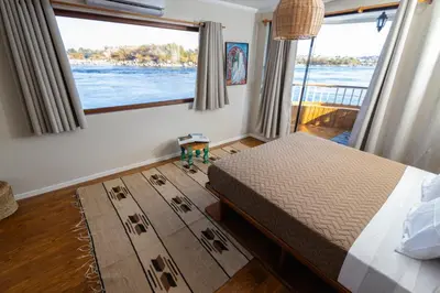 a bedroom with a bed and a large window at Escaleeh Dahabiya Tranquil sailing in Jazīrat Suhayl
