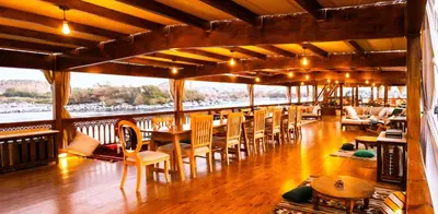 a restaurant with tables and chairs on a balcony at Escaleeh Dahabiya Tranquil sailing in Jazīrat Suhayl