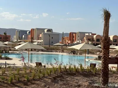 a resort with a pool with umbrellas and a palm tree at Luxurious 3Bd Living Awaits in El Gouna in Hurghada