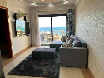a living room with a couch and a view of the ocean at Palm View Paradise-Downtown Hurghada in Hurghada