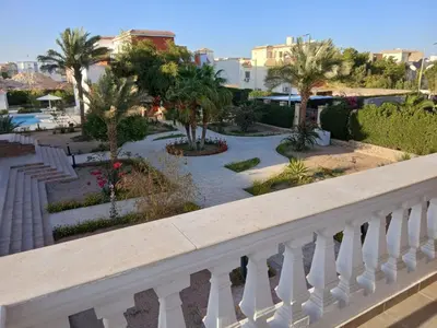 a balcony with a view of a park with palm trees at Cozy Villa in Hurghada
