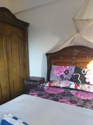 a bedroom with a bed with a wooden headboard at Ziggy Marley Backpackers Hostel in Al Aqālitah