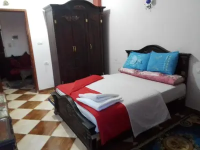 a bedroom with a large bed with blue and red pillows at Ziggy Marley Backpackers Hostel in Al Aqālitah