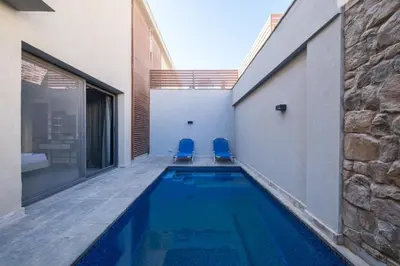 a swimming pool with two blue chairs next to a building at Luxury 2BR Bali • Heated Pool in Hurghada