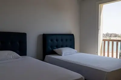 two beds sitting next to a window in a bedroom at Exquisite 2 Bdr Apartment Waterside in Hurghada