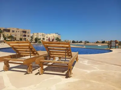 two wooden chairs sitting next to a swimming pool at Blue Lagoon View - 2 Bed 2 Bath - Shared Pool - El Gouna in Hurghada