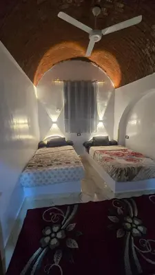 two beds in a room with a ceiling at Isis Nubian Services in Jazīrat Aswān