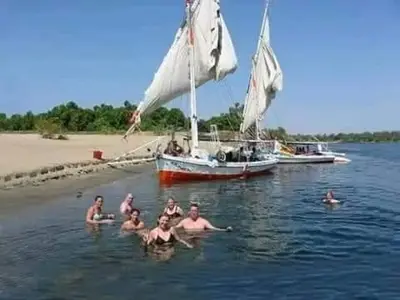 a group of people in the water with a sail boat at Isis Nubian Services in Jazīrat Aswān