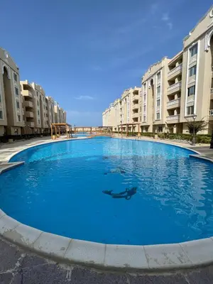 a large blue swimming pool in front of some buildings at Aven Resort Compound in Hurghada