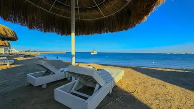 a beach with two lounge chairs and an umbrella at Elite AlDaU Heights in Hurghada