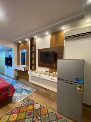 a kitchen with a refrigerator and a flat screen tv at شقه فردين مطله علي حمام السباحه في الغردقه in Hurghada
