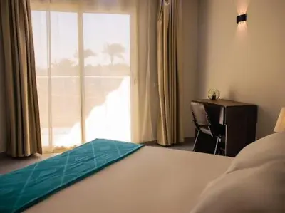 a bedroom with a bed and a desk and a window at Hurghada Scandic in Hurghada