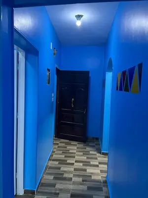 a hallway with blue walls and a black door at AnDy Nubian Guest House in Aswan