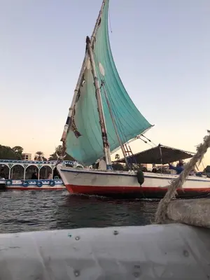 a boat with a green sail in the water at luxor in Luxor