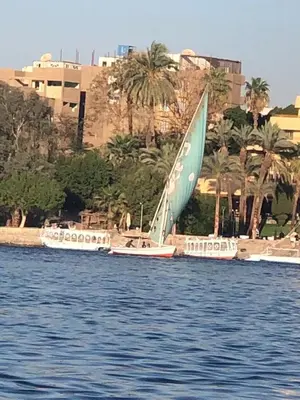 three boats with a sail on the water at luxor in Luxor